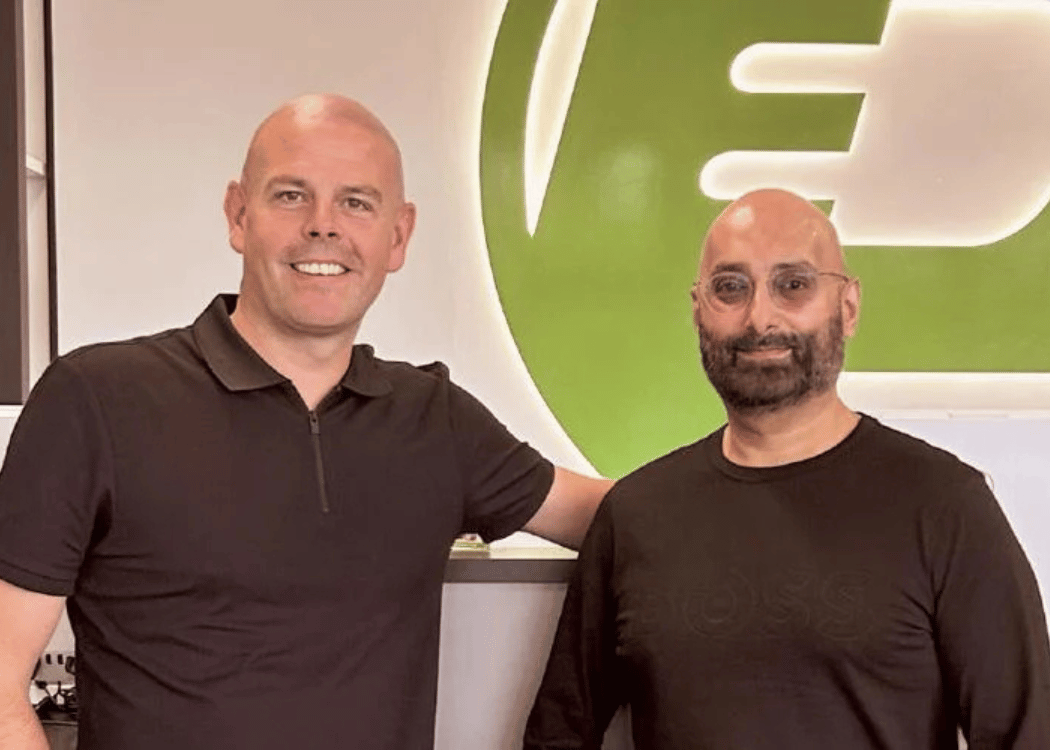 Two men wearing black shirts standing indoors with a green and white PayMore logo in the background